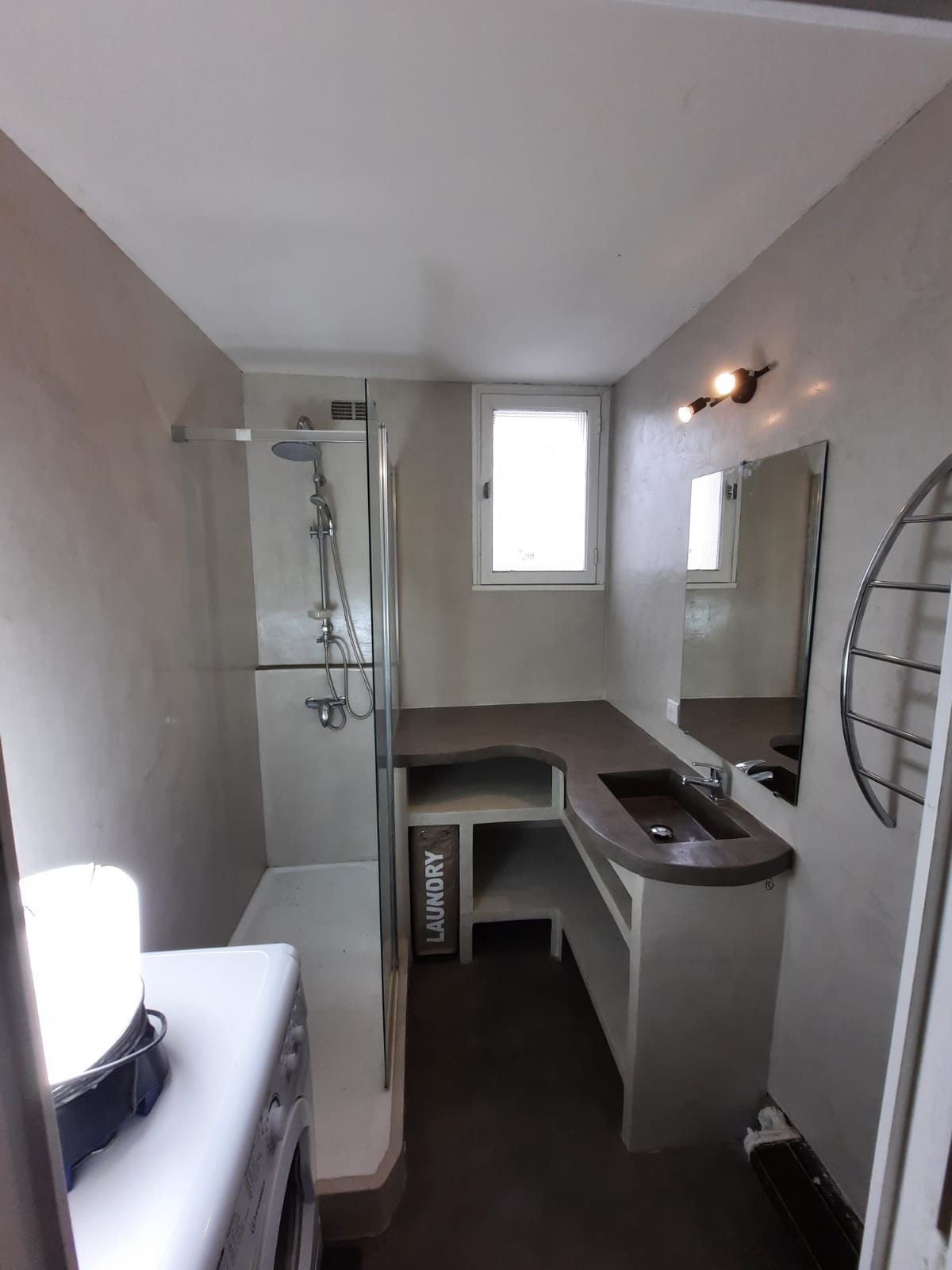 des murs clairs et un meuble vasque aux courbes minérales.