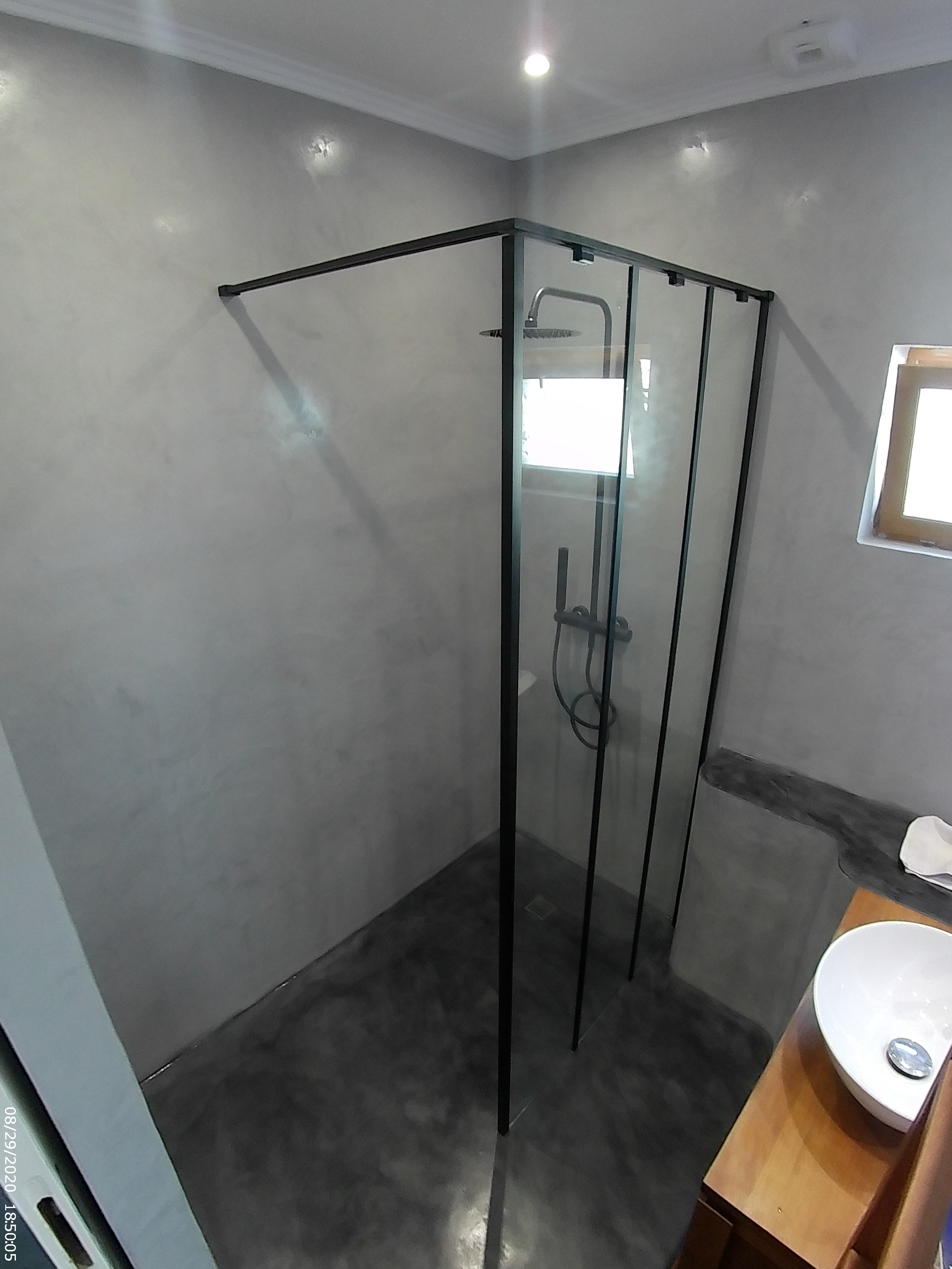La douche vitrée se détache sur les finitions grises.