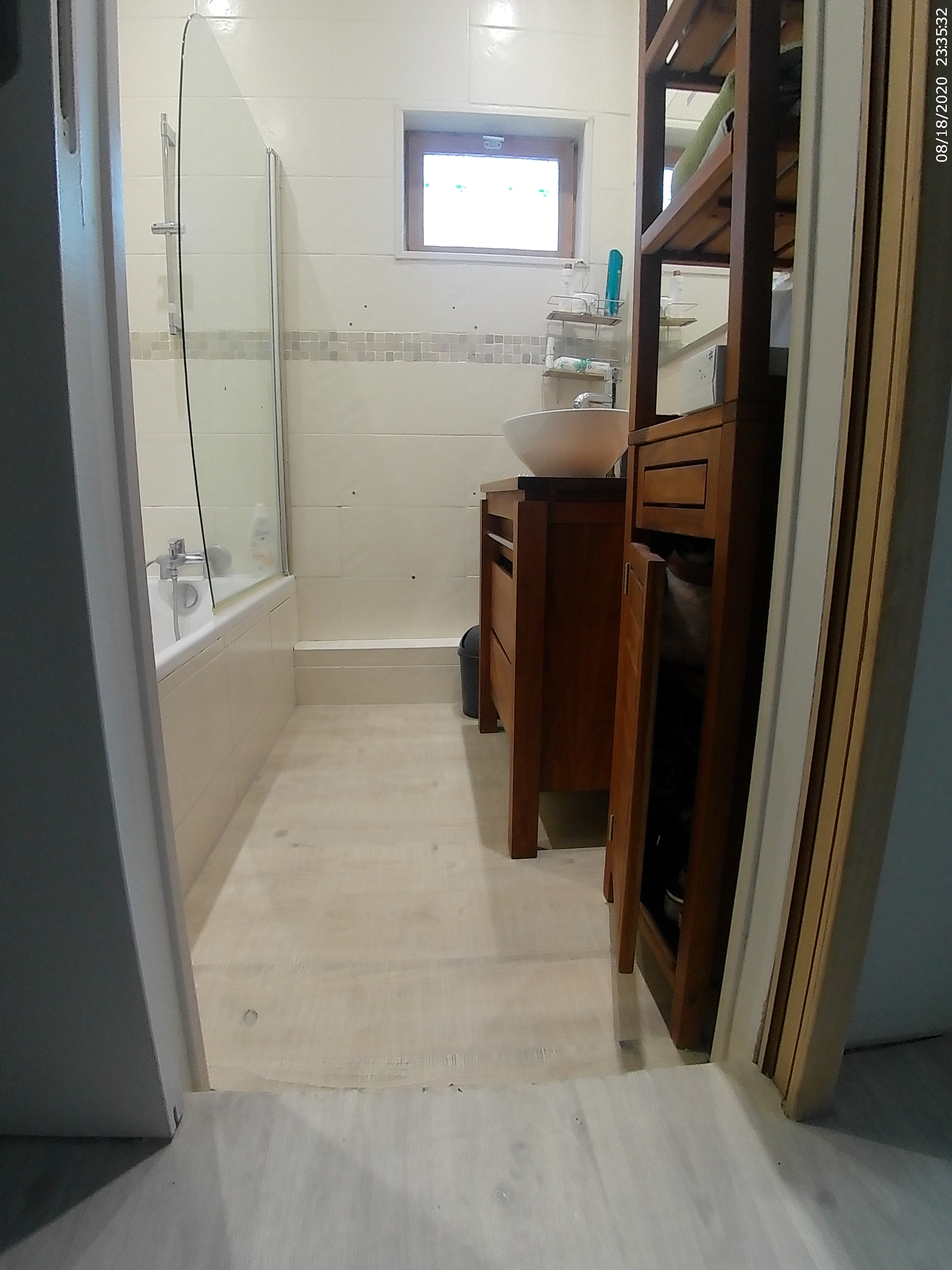 carrelage clair et paroi de douche à cadre blanc.