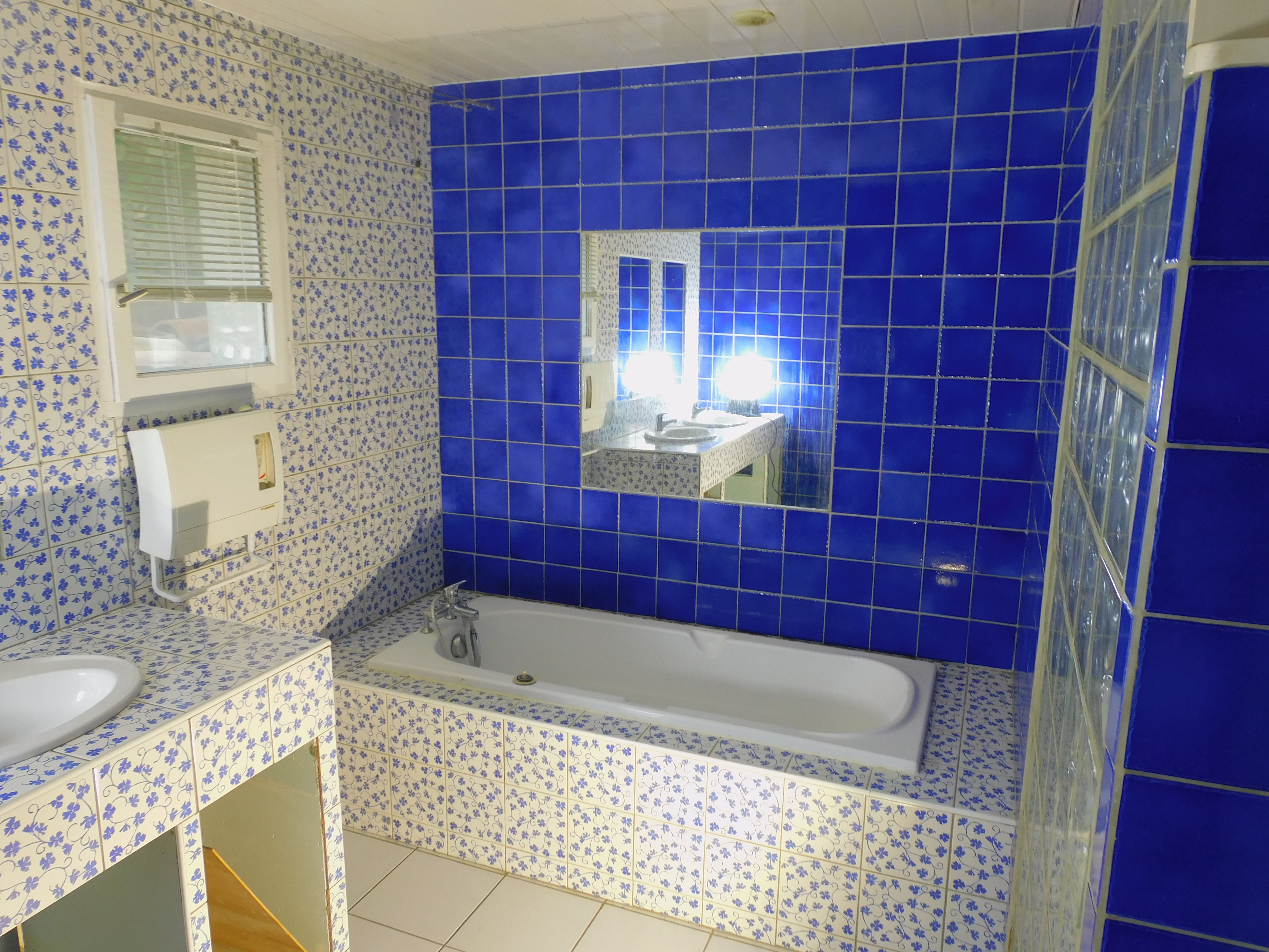 une baignoire encastrée entourée de carrelage bleu.