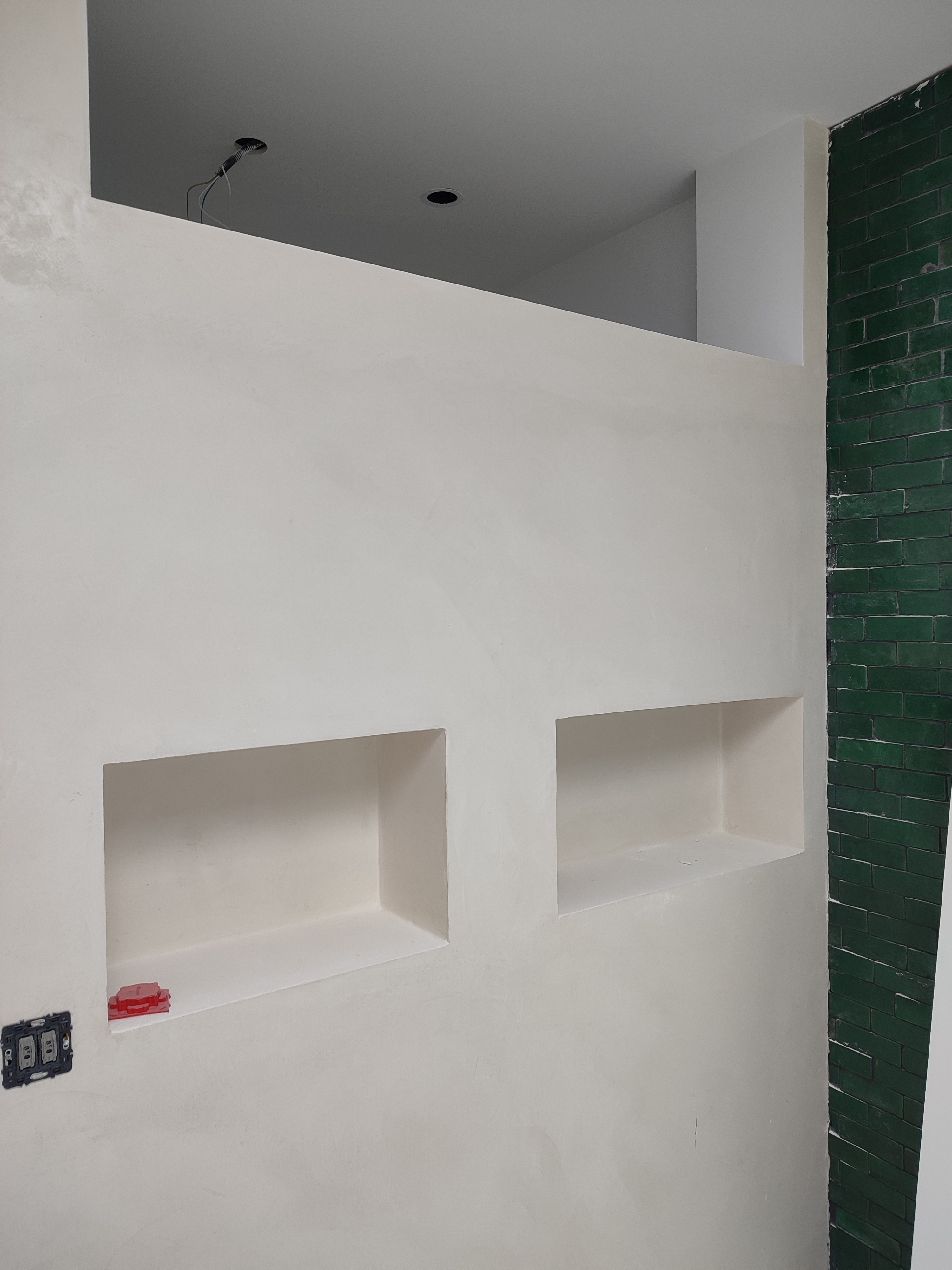 Les niches intégrées à la cloison, à côté du mur vert de la douche.