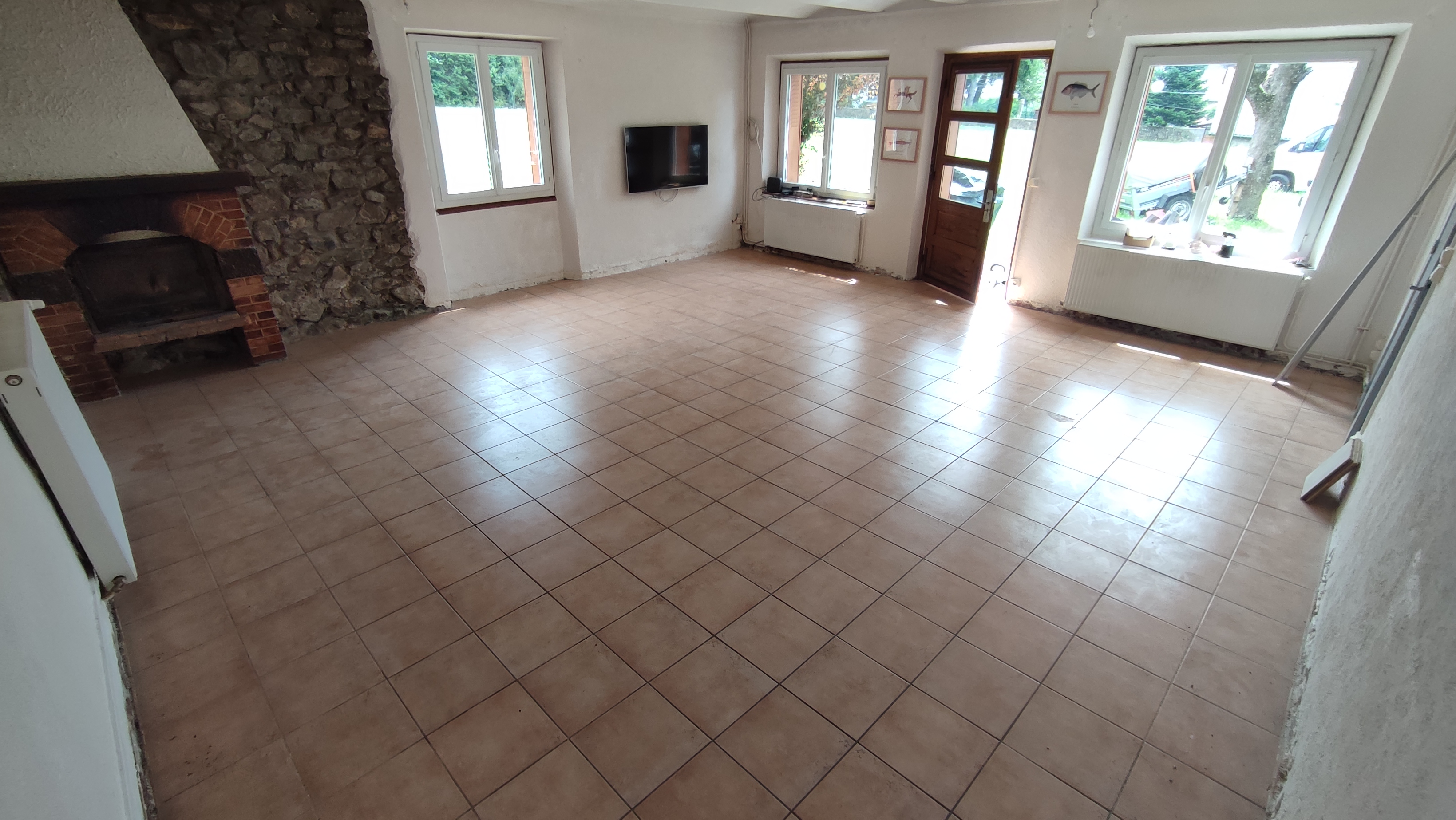 Avant — le carrelage brun quadrille le sol de la pièce de vie.