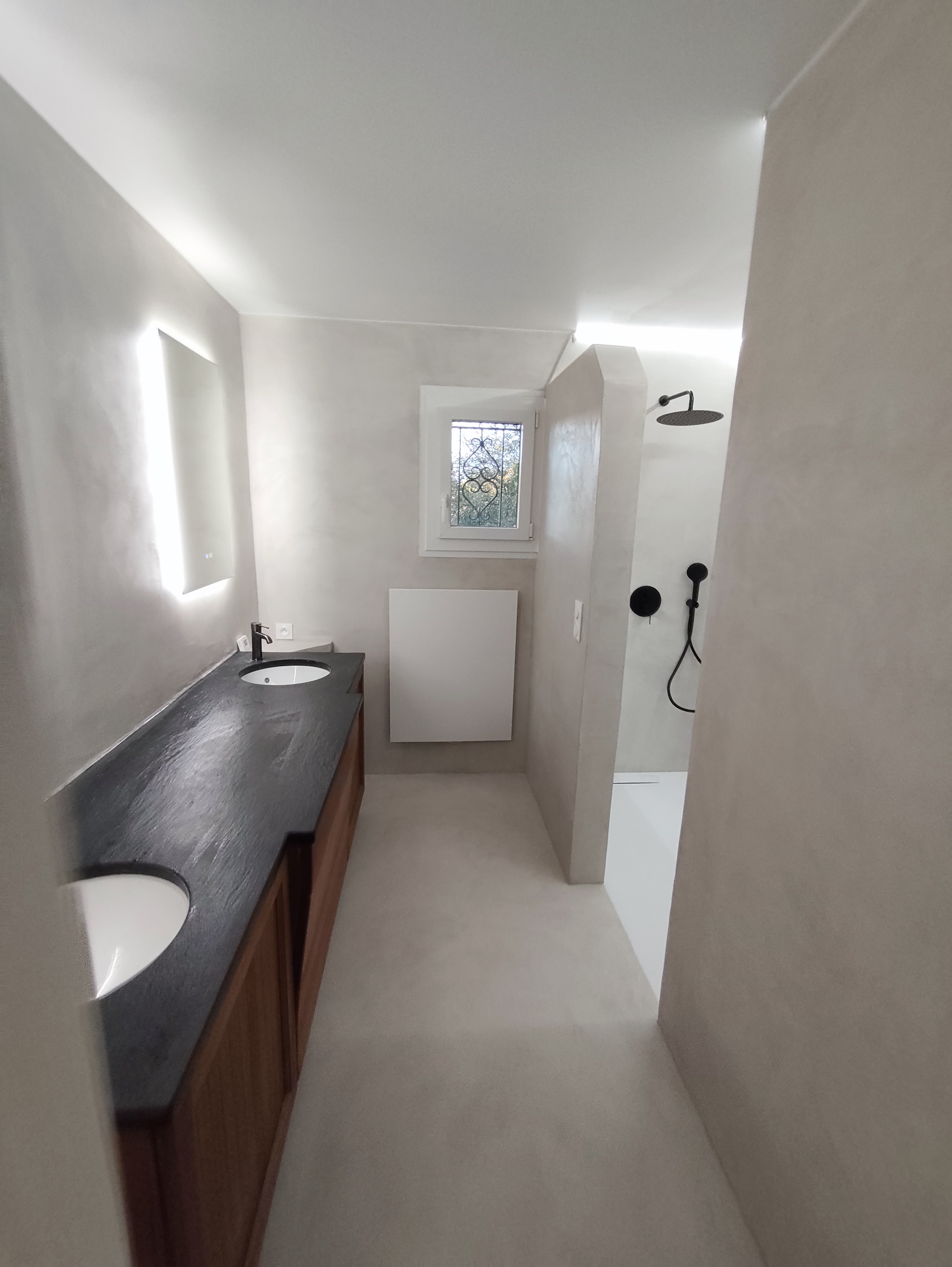 Salle d’eau de Poliénas après rénovation : douche et béton ciré