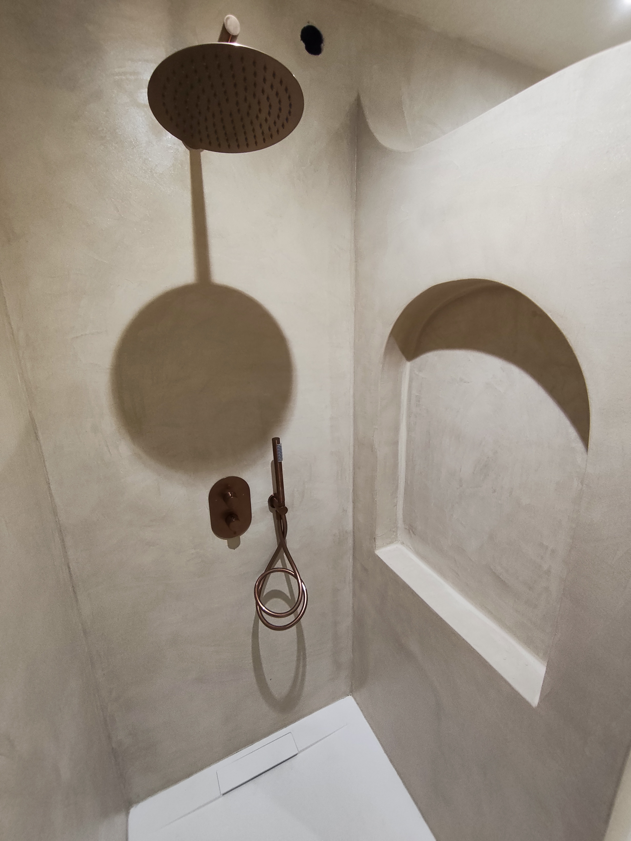 Douche à Saint-Jean-le-Vieux avec niche arrondie, murs minéraux clairs et robinetterie couleur bronze